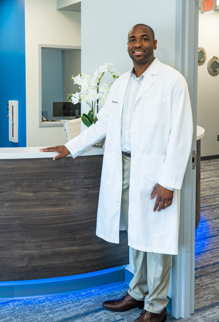 Dr. Kareem Redmond DDS standing in front desk reception area of Blue Wolf Dental